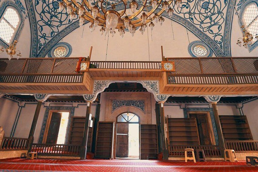 Ein prachtvoller Innenraum mit einer großen Chandelier, hölzernen Balkonen und aufwendigen blau-weißen Mustern an den Wänden. 5