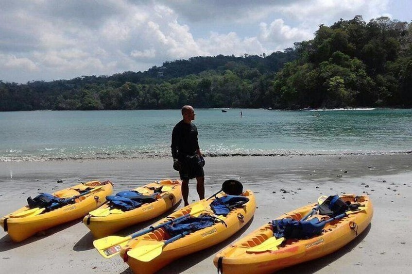 A man standing on a beach with kayaks lined up. 3
