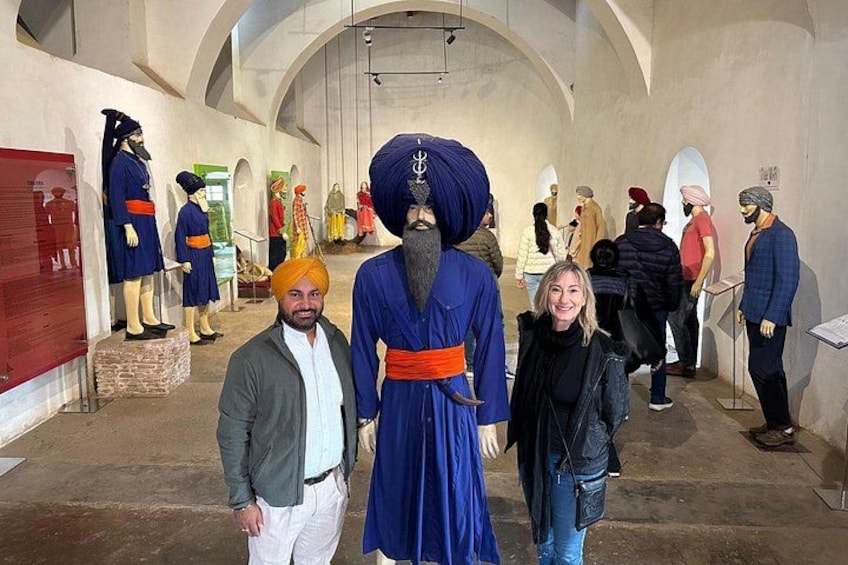 Ein Museumsinnenraum mit Mannequins in traditioneller Tracht, einem Mann mit Turban und einer Frau in Freizeitkleidung. 3