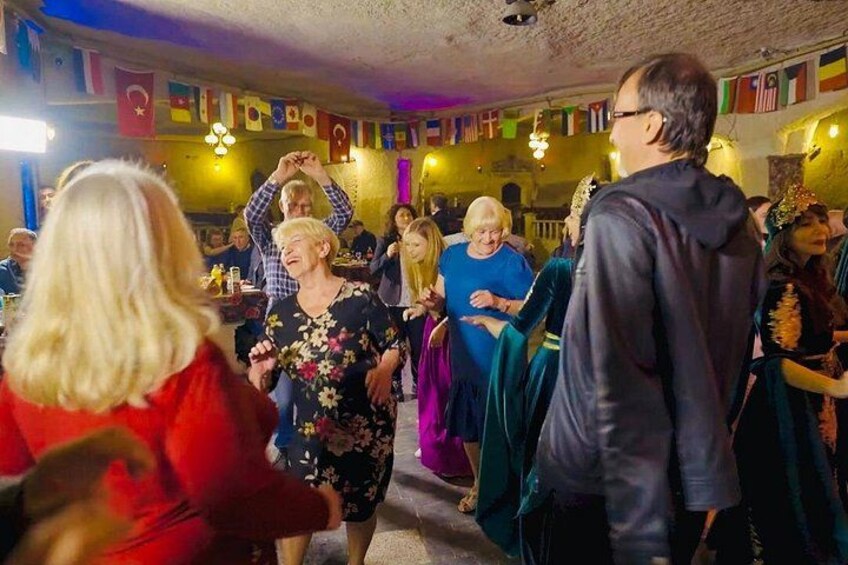 A group of people dancing in a room with flags hanging on the wall. 2