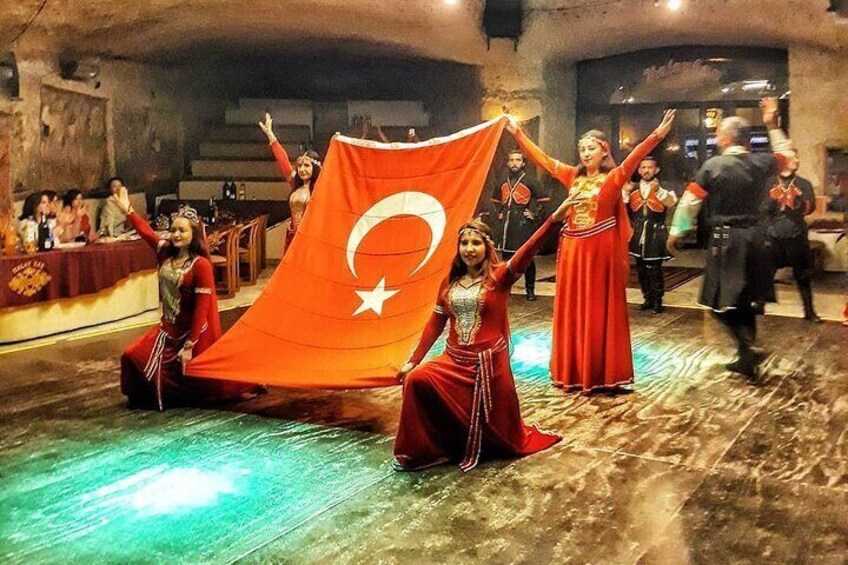A group of people in traditional attire performing a dance with a flag. 1