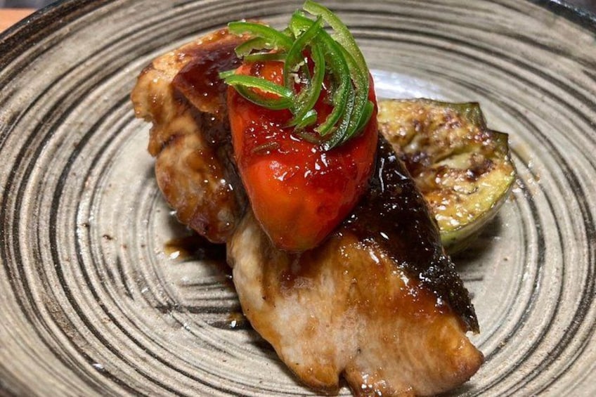 Un plato con carne a la parrilla, una rodaja de tomate y una porción de berenjena asada. 2
