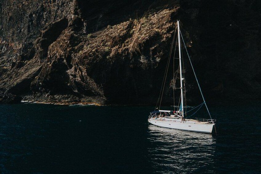 Ein Segelboot auf ruhigem Wasser vor einer felsigen Küste. 1