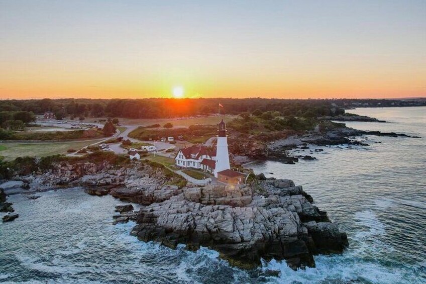 A lighthouse on a rocky outcrop with a sunset in the background. 4