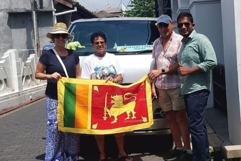 Quatre personnes tenant un drapeau devant un véhicule blanc. 4