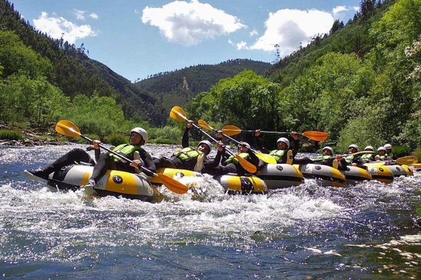 A group of people rafting on a river surrounded by green hills. 4