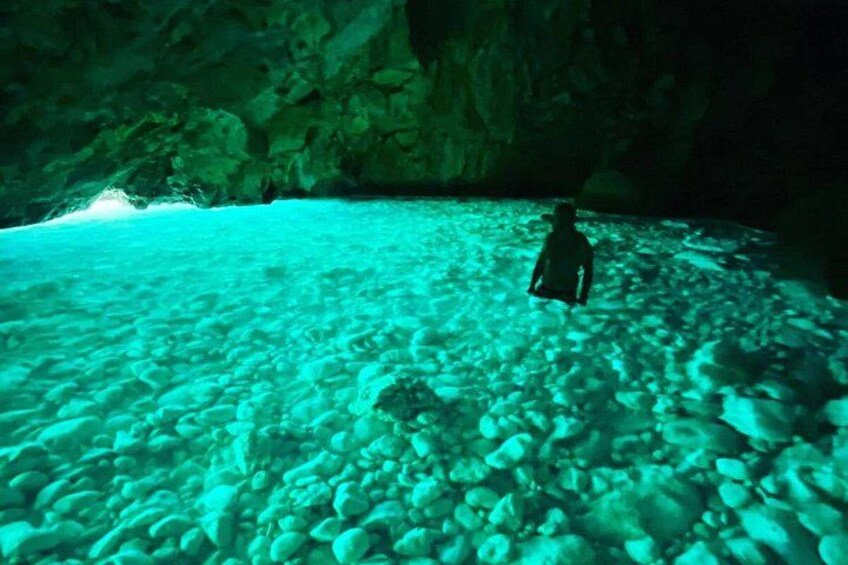 Une personne faisant de la plongée avec tuba dans une grotte sous-marine aux eaux claires, parsemée de formations rocheuses. 4