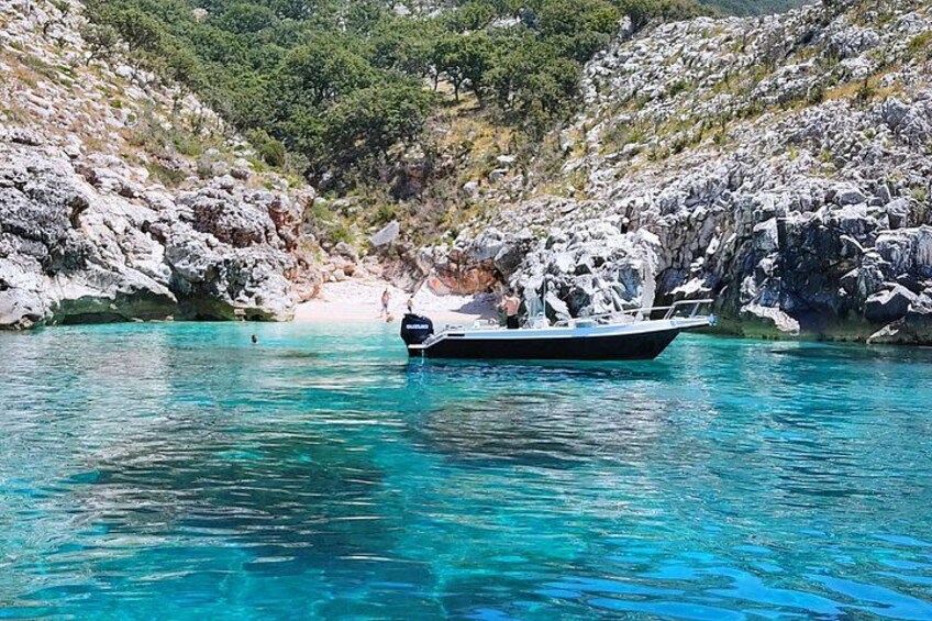 Un bateau sur une eau turquoise et limpide, avec des falaises rocheuses en arrière-plan. 3