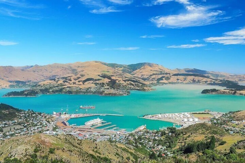 A coastal town with a turquoise bay, a pier, and a mountain range in the background. 1
