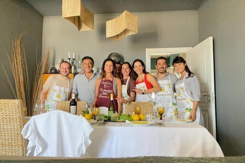 Un grupo de personas sentadas a una mesa con mantel blanco, copas de vino y botellas. 1