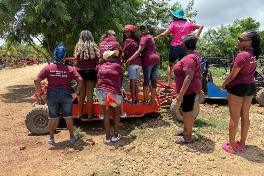 Un grupo de personas con camisas color caqui de pie alrededor de un tractor rojo en un camino de tierra. 2