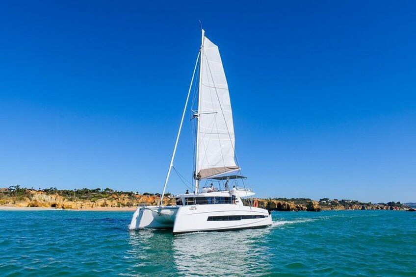 A white sailboat with a single mast sailing on calm blue waters. 2