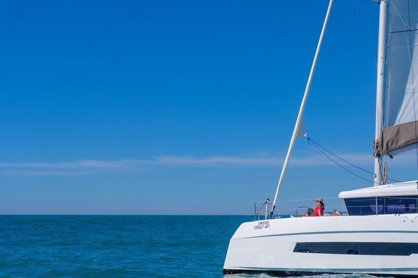 Un yate blanco con un solo mástil navega sobre aguas azules tranquilas bajo un cielo despejado. 3