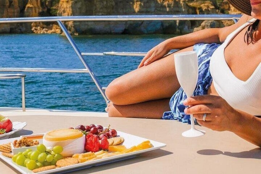 A person on a boat with a plate of food and a glass of drink. 2