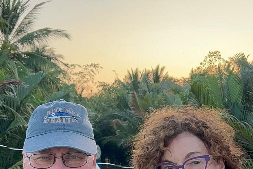 A person wearing a cap with text and a tropical background with palm trees. 5