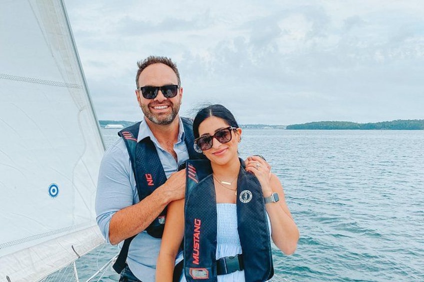 Two people on a sailboat wearing life jackets with the brand 'MYSTANG' visible. 4
