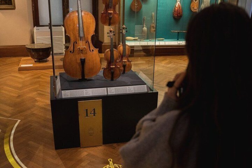 A violin on display in a museum, with other string instruments in the background. 3