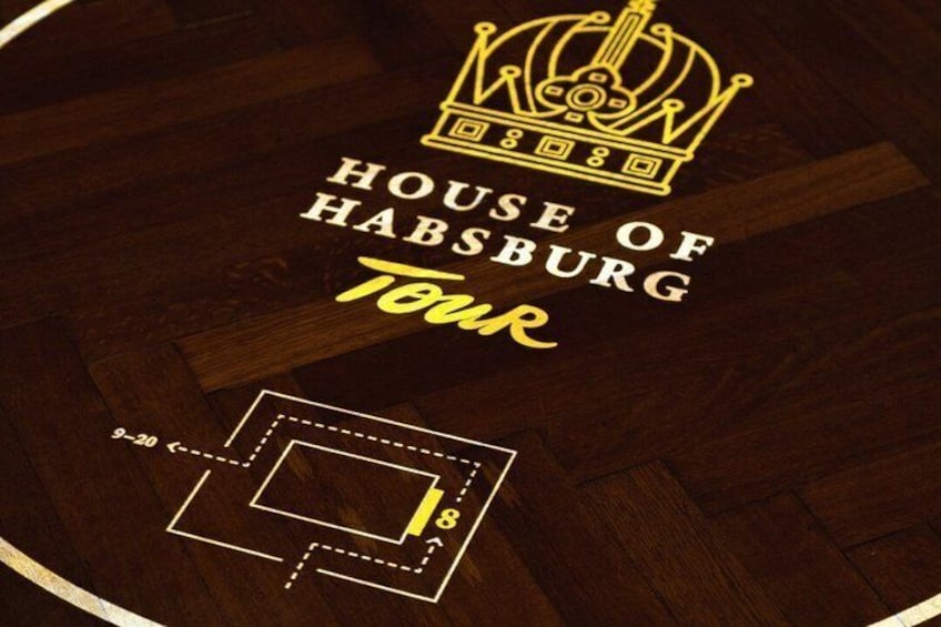 A wooden floor with a crown emblem and text reading 'House of Habsburg Tour.' 5
