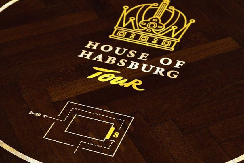 Een houten vloer met een kroonembleem, de tekst 'House of Habsburg Tour' en een plattegrond. 4