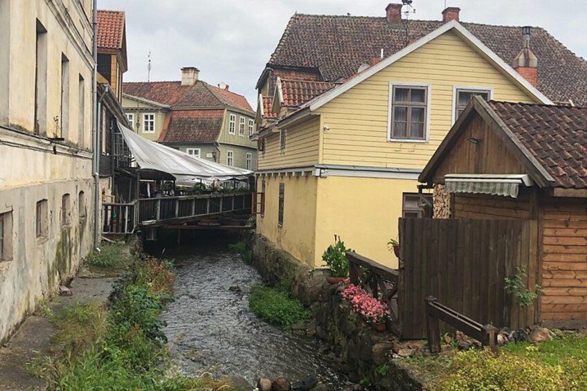 Ein schmaler Kanal mit einer Brücke, umgeben von Gebäuden mit roten Ziegeldächern. 4