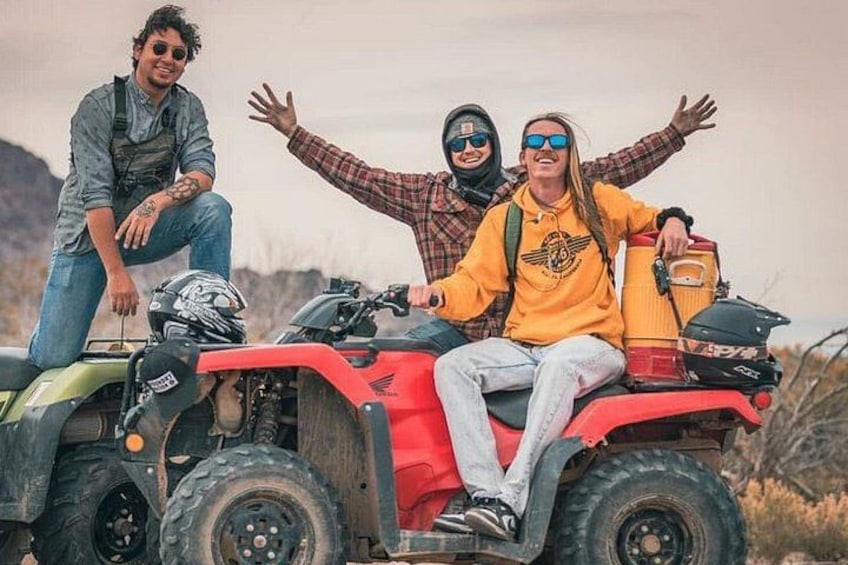 Tres personas en un vehículo todo terreno con un paisaje montañoso al fondo. 3
