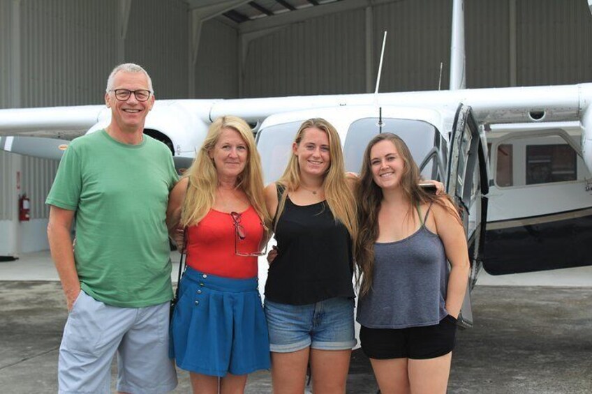 Four people standing in front of a small aircraft in a hangar. 4