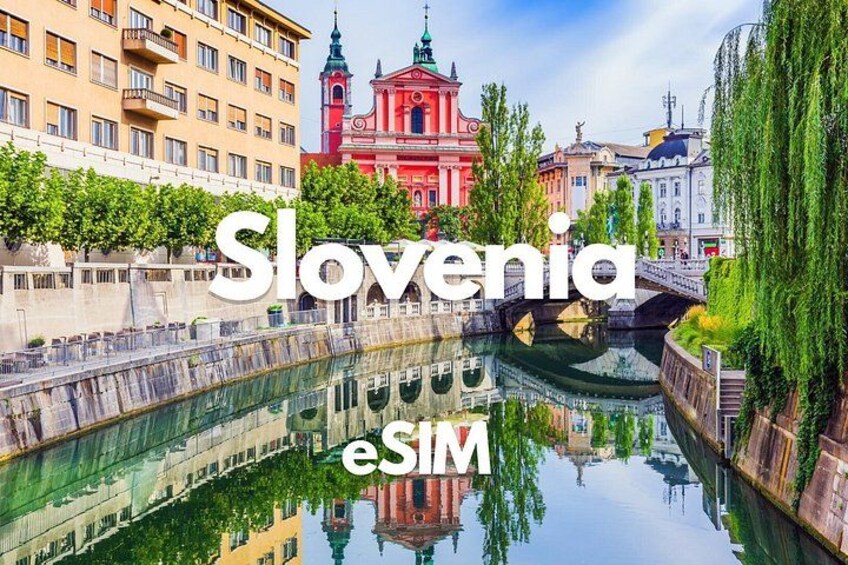 A canal with buildings and a red church in Slovenia. 1