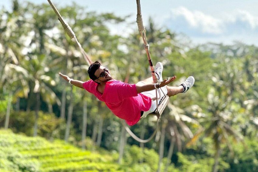 A person swinging on a rope swing in a lush, green environment. 2