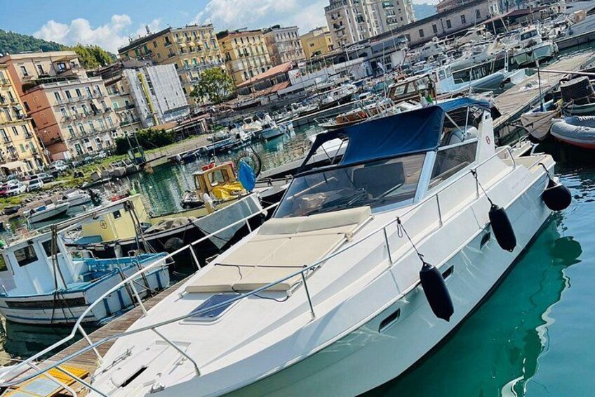 A marina with boats docked, buildings in the background, and a clear sky. 1