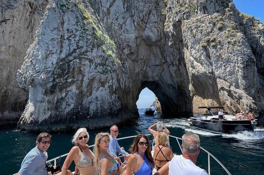 A boat tour with people enjoying a rocky coastal landscape and a natural arch formation. 2