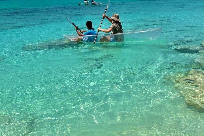 Two people paddling in a clear blue water canoe. 2