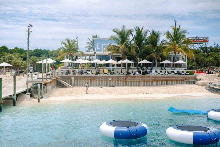 A beachside restaurant with outdoor seating, palm trees, and floating docks. 3