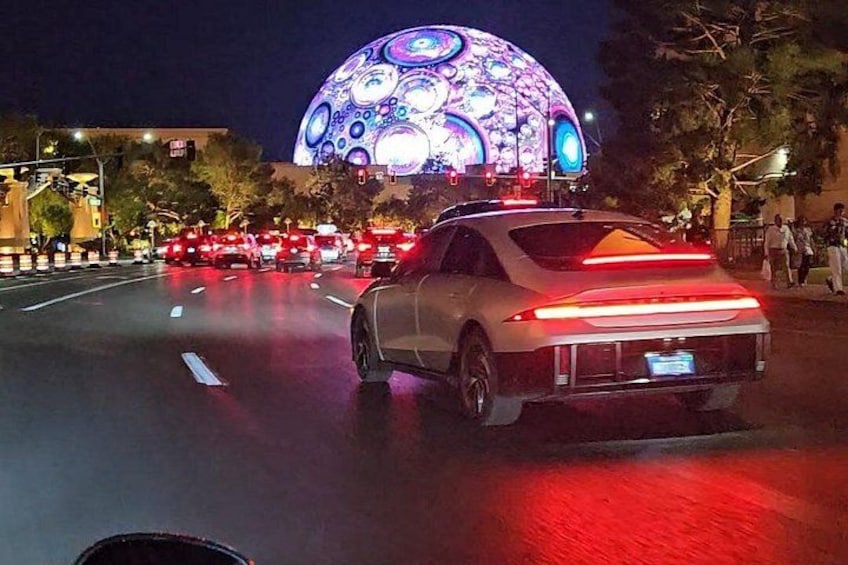 Un auto deportivo blanco circulando por una calle de la ciudad de noche. 2