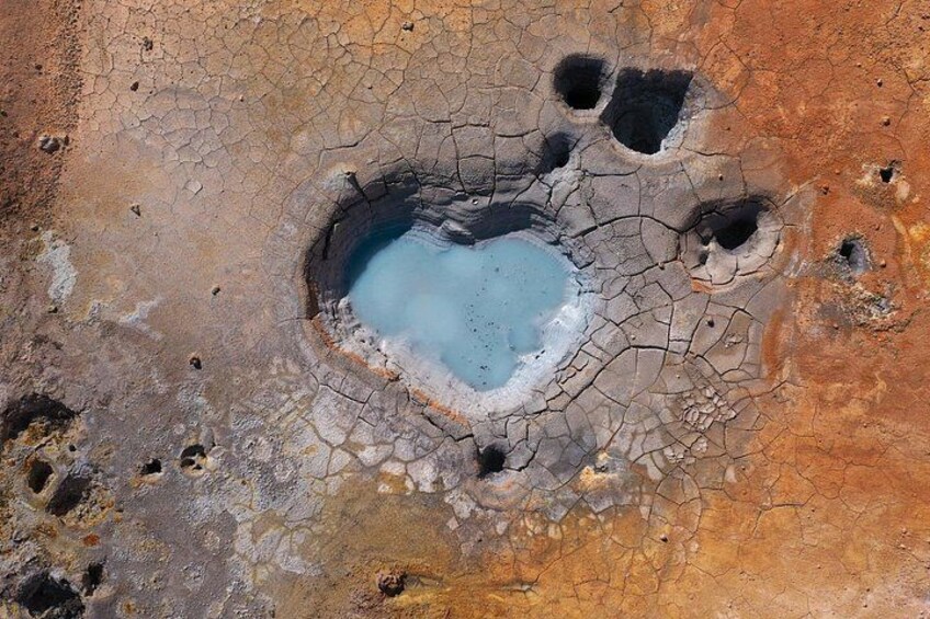 Un grand cratère au centre bleu, entouré d’une terre craquelée et de divers petits trous. 4