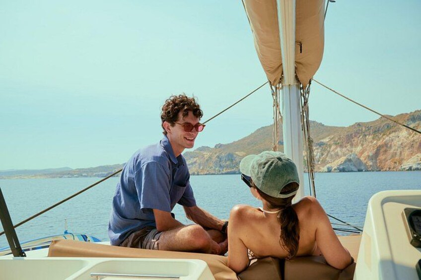 Una persona en un bote, otra sentada en la cubierta, y un paisaje montañoso al fondo. 2