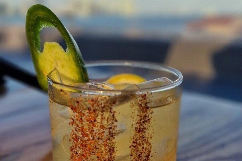 En cocktail garnerad med en limeskiva och en citronskiva, serverad i ett genomskinligt glas. 2