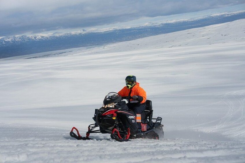 Eine Person fährt mit einem Schneemobil durch eine verschneite Landschaft. 3