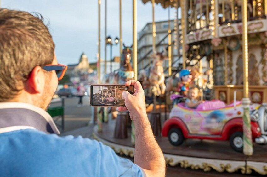 A carousel with colorful horses and a person taking a photo. 2