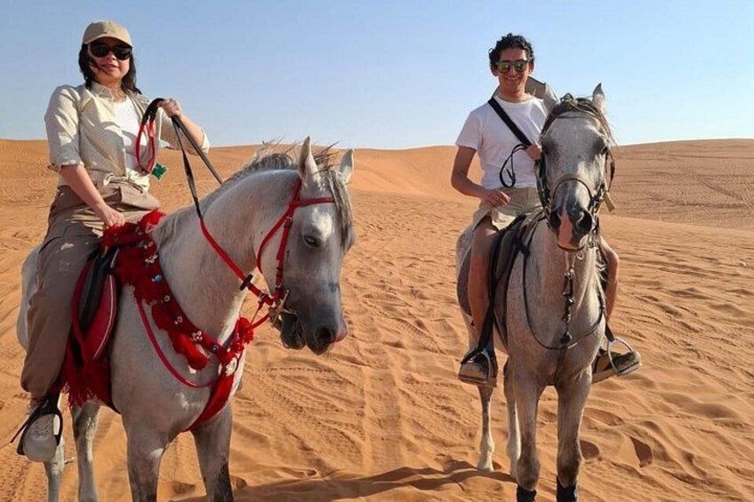 Two people riding horses in a desert. 5