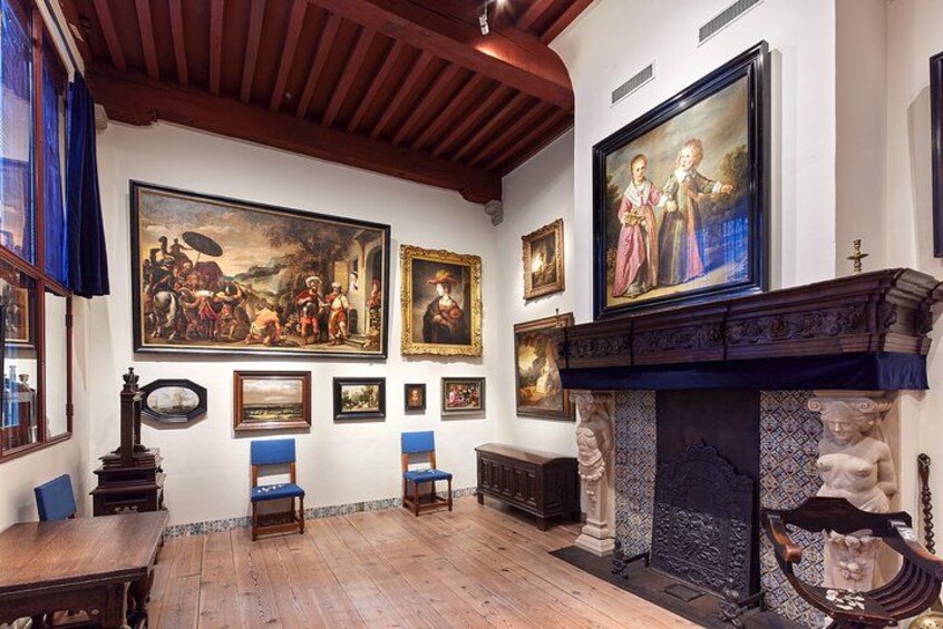 Una habitación con pisos de madera, chimenea y varias obras de arte enmarcadas en las paredes. 2