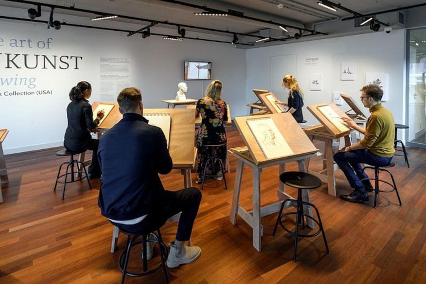 Una mostra d'arte con persone che osservano opere su cavalletti. 4