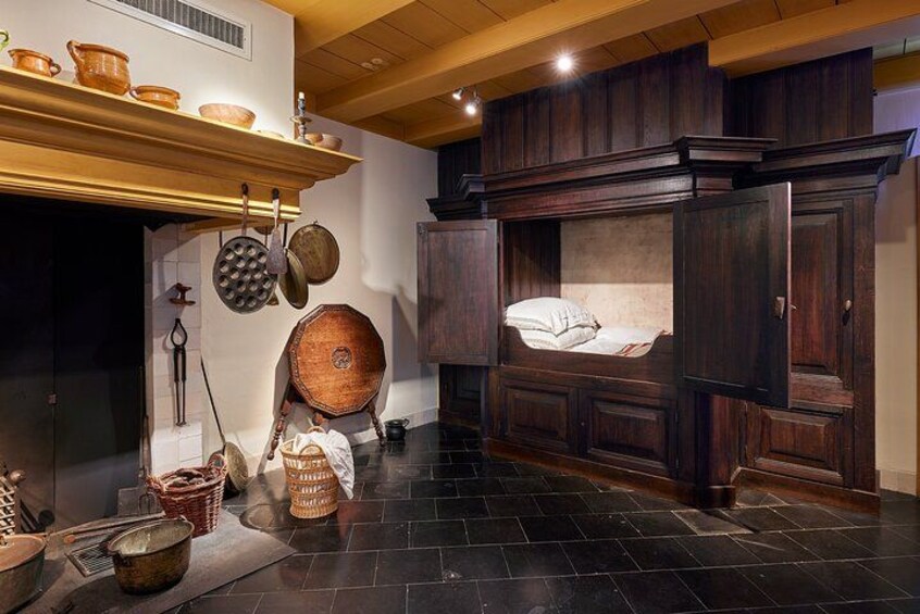 Una cocina rústica con armarios de madera, un colgador para ollas y un suelo de piedra. 3
