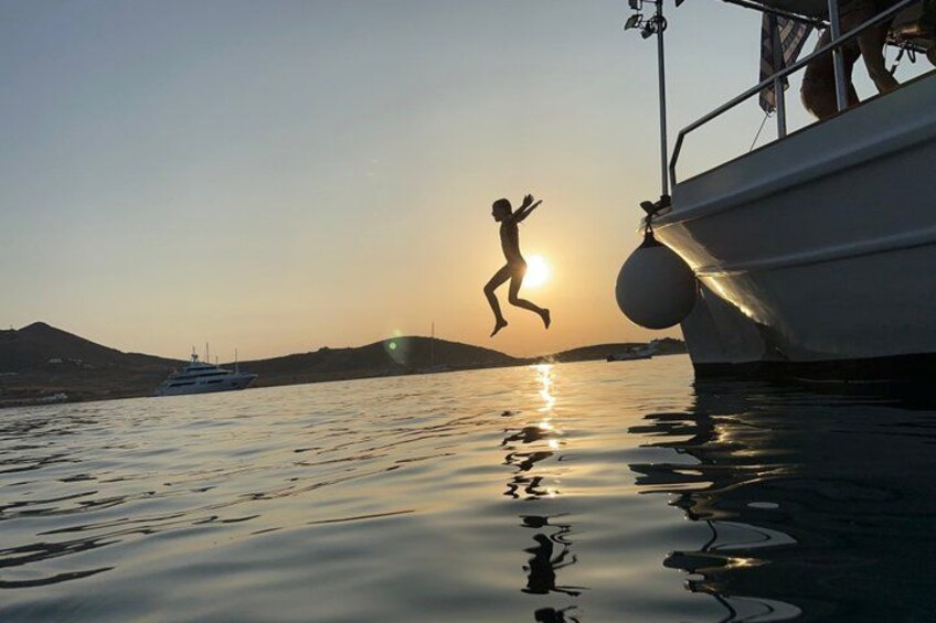 Iemand springt bij zonsondergang van een boot. 4