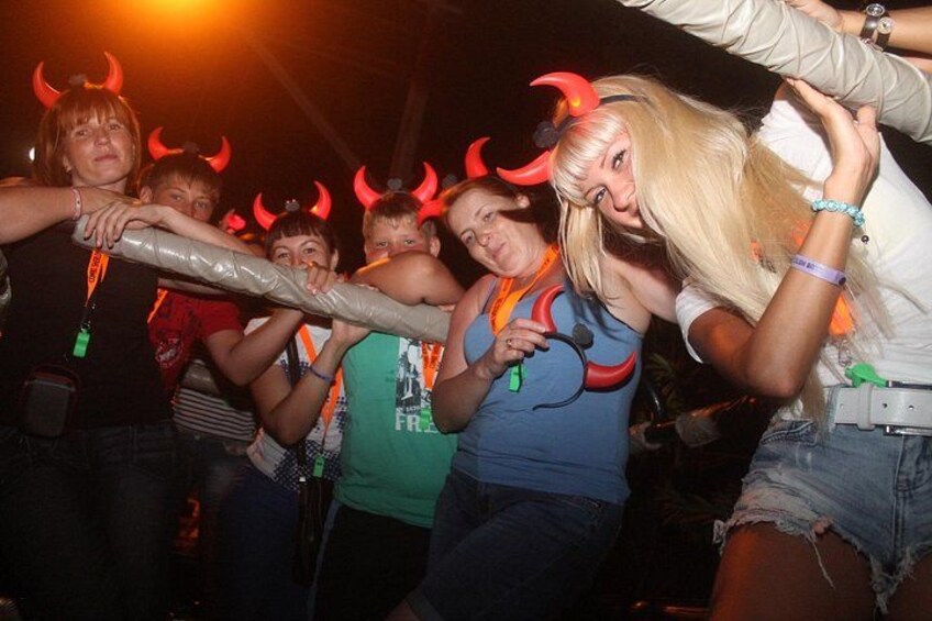 Personas bailando, algunas con cuernos de diablo y una persona sosteniendo un bate. 2