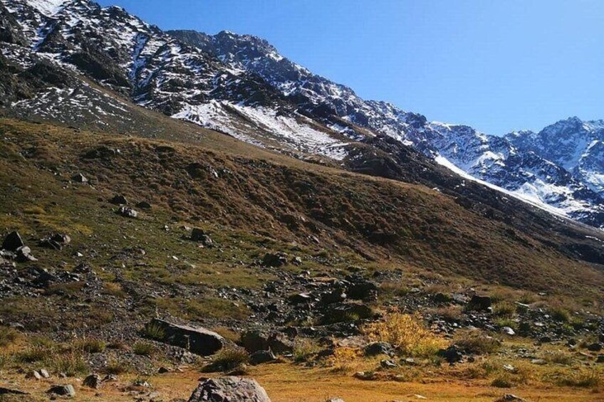 A mountainous landscape with rocky terrain, sparse vegetation, and snow-capped peaks. 4