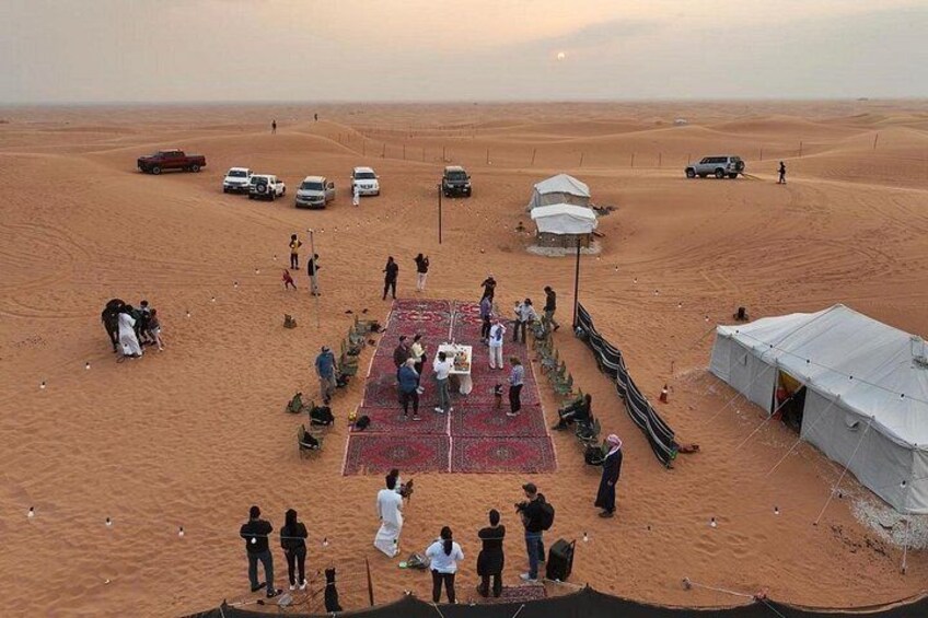 A desert landscape with tents, a central gathering area, and vehicles. 4