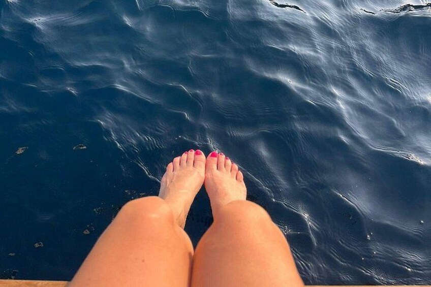 Benen met roze gelakte teennagels die rusten op een wateroppervlak. 5