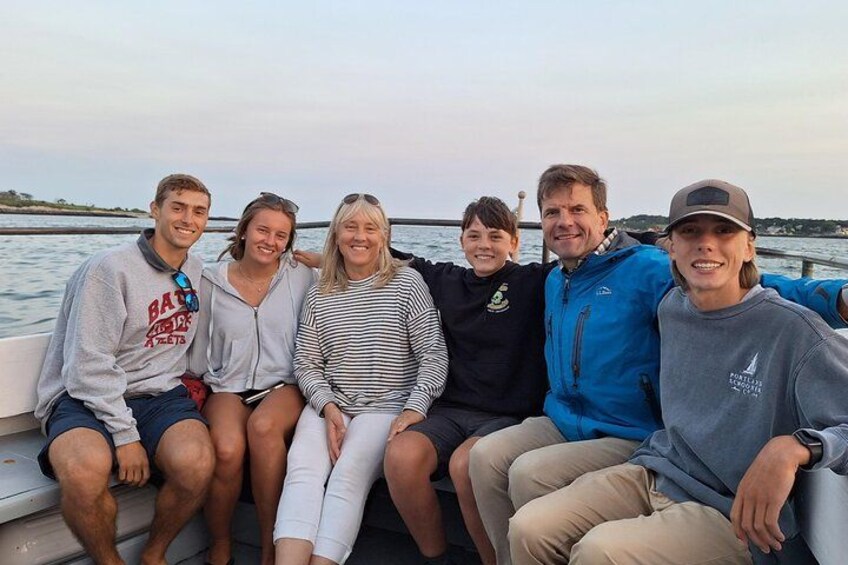 Un groupe de personnes se trouve sur un bateau, avec de l’eau autour et une côte lointaine en arrière-plan. 3