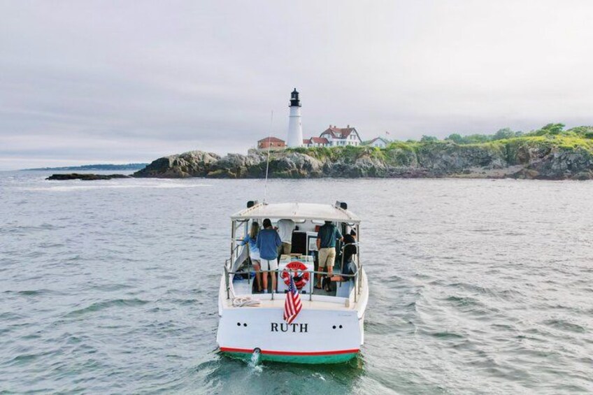 Un bateau nommé RUTH navigue sur une eau calme, avec un phare en arrière-plan. 4