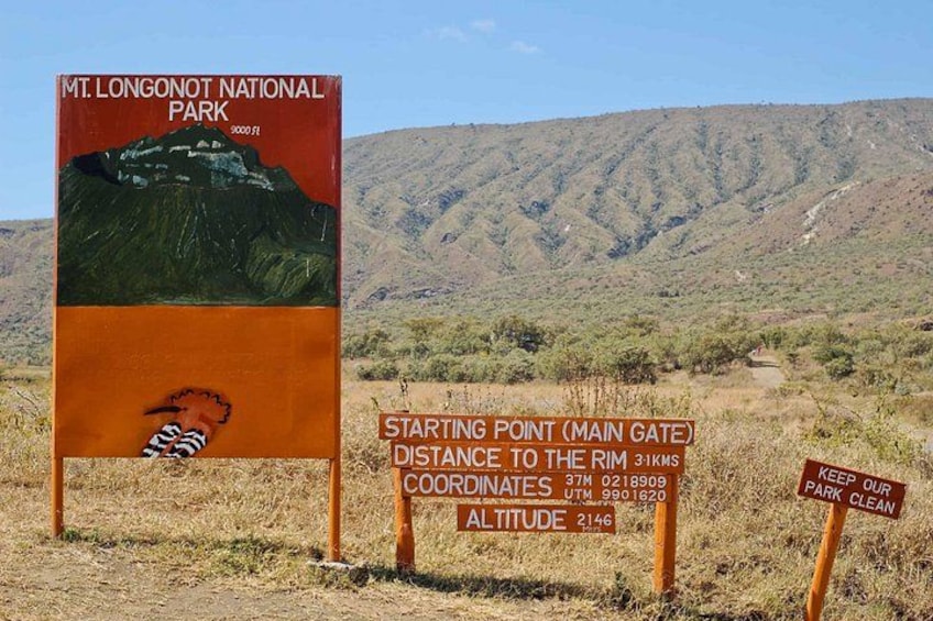 Een bordje voor Nationaal Park Mt. Longonot, met een berg op de achtergrond. 1